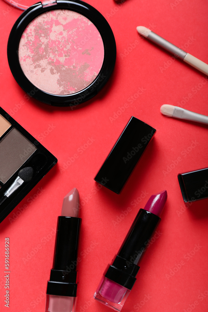 Set of decorative cosmetics with lipsticks on red background, closeup