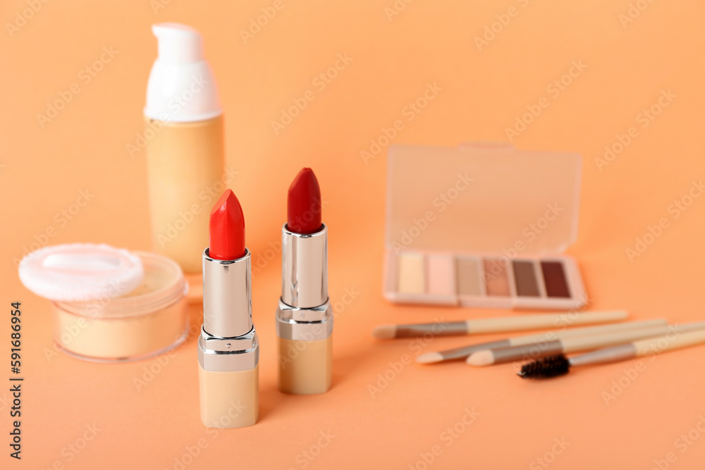 Set of cosmetic products with lipsticks on color background