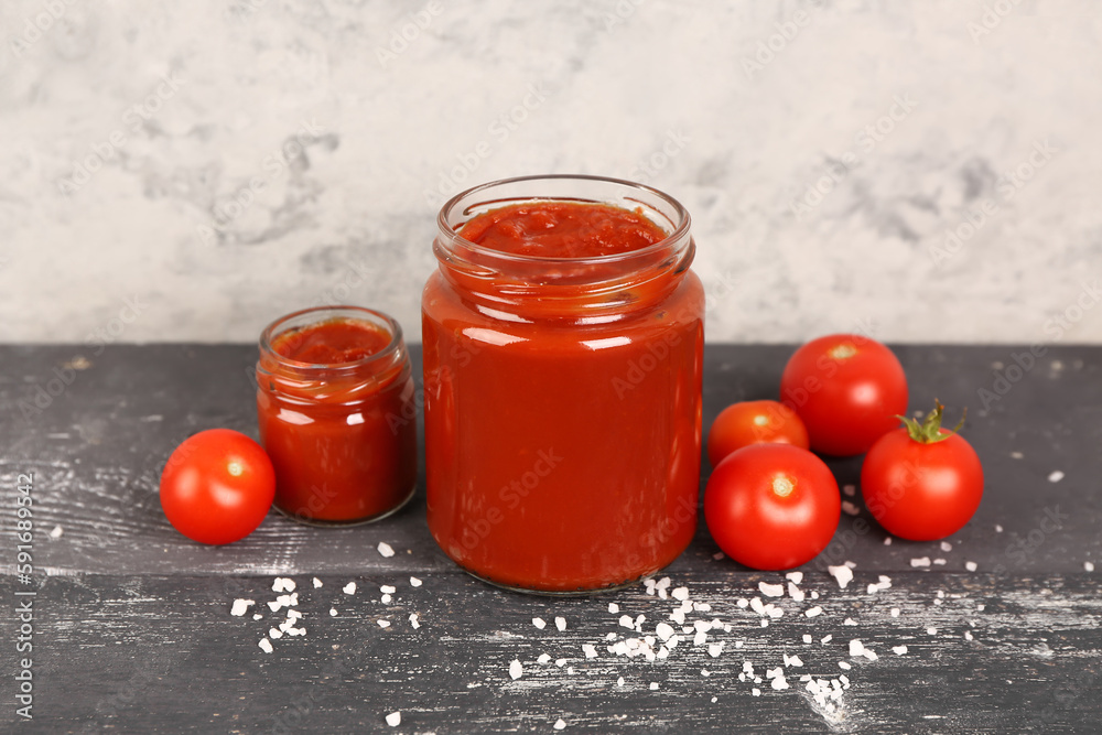 Jars with tasty tomato paste and fresh vegetables on table