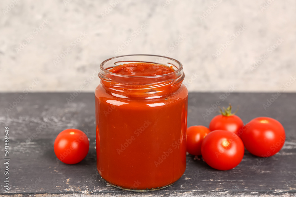 Jar with tasty tomato paste on table