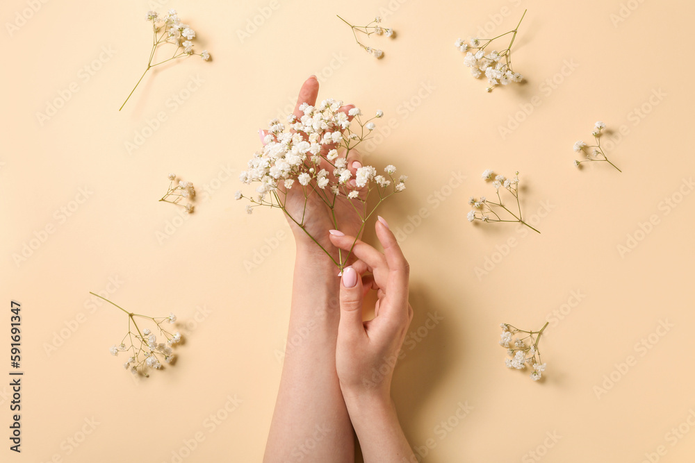 Woman with gypsophila flowers on beige background. Hand care concept