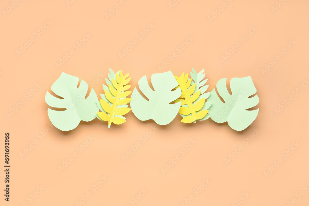 Paper tropical leaves on orange background