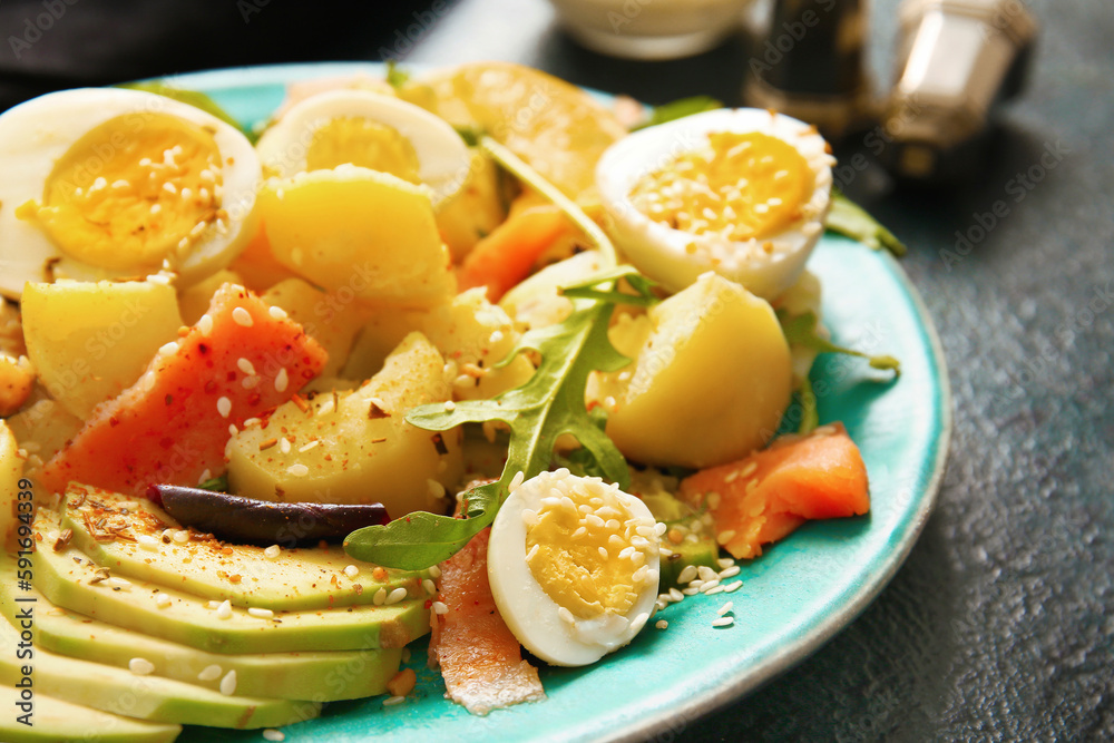 Plate of tasty potato salad with eggs and avocado on dark background, closeup