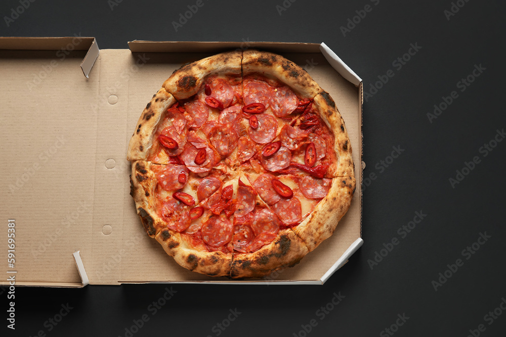 Cardboard box with delicious pepperoni pizza on black background