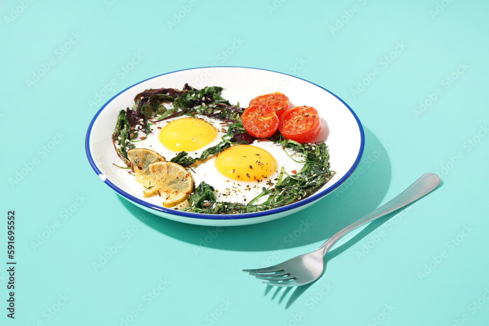 Plate with tasty fried eggs and salad on blue background