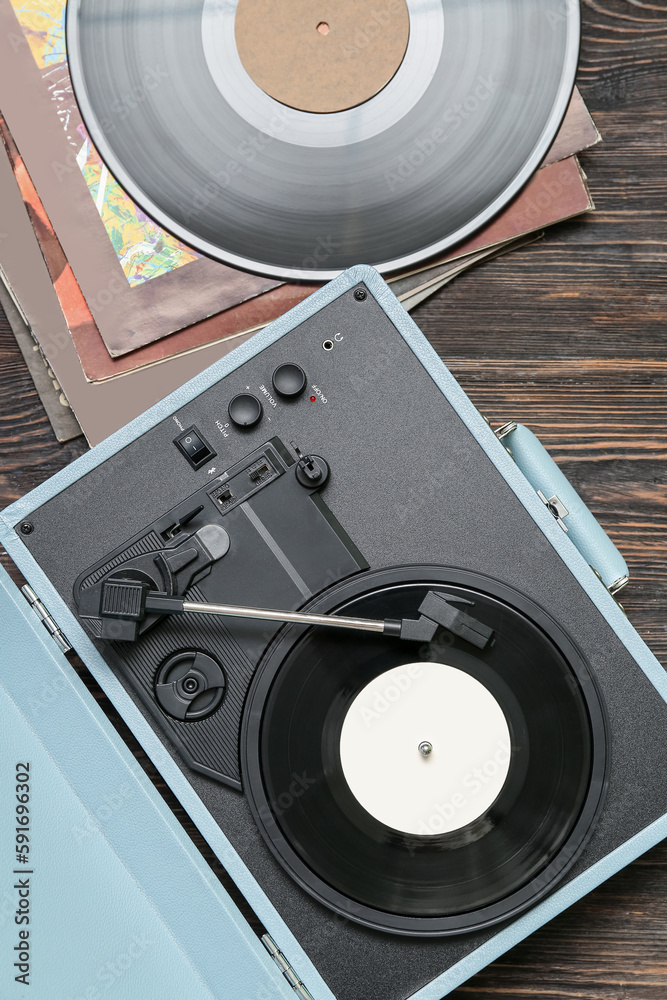 Record player with vinyl disks on dark wooden background