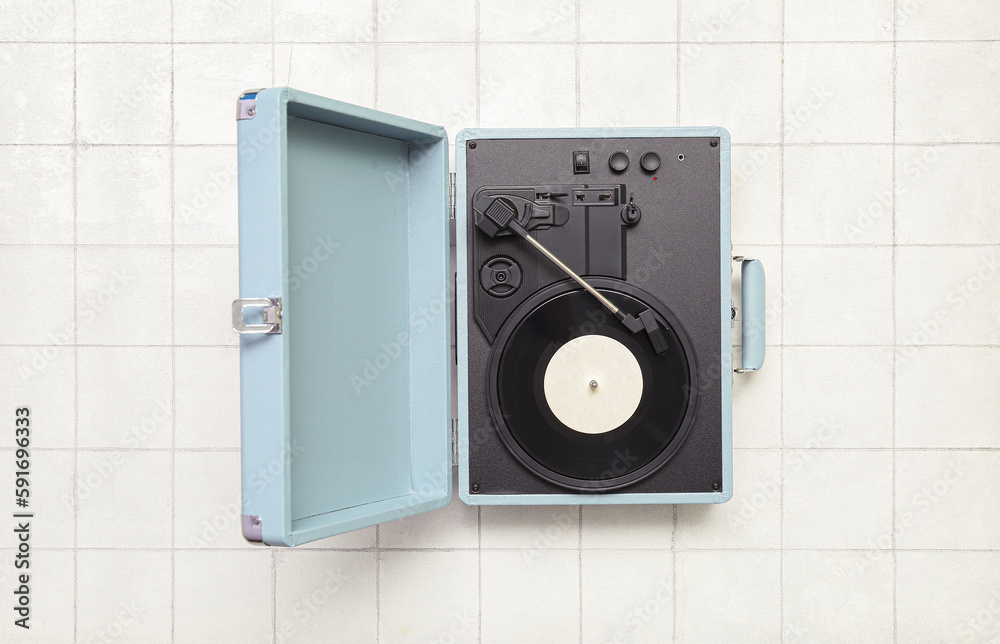 Record player with vinyl disk on white tile background