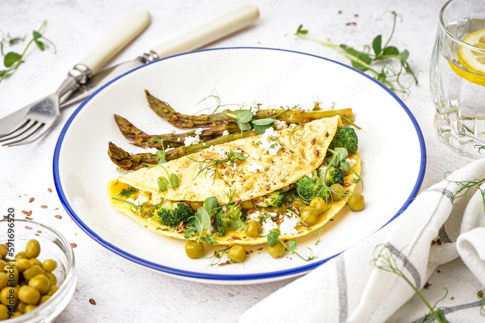 Tasty omelet with broccoli, asparagus and pea on light table