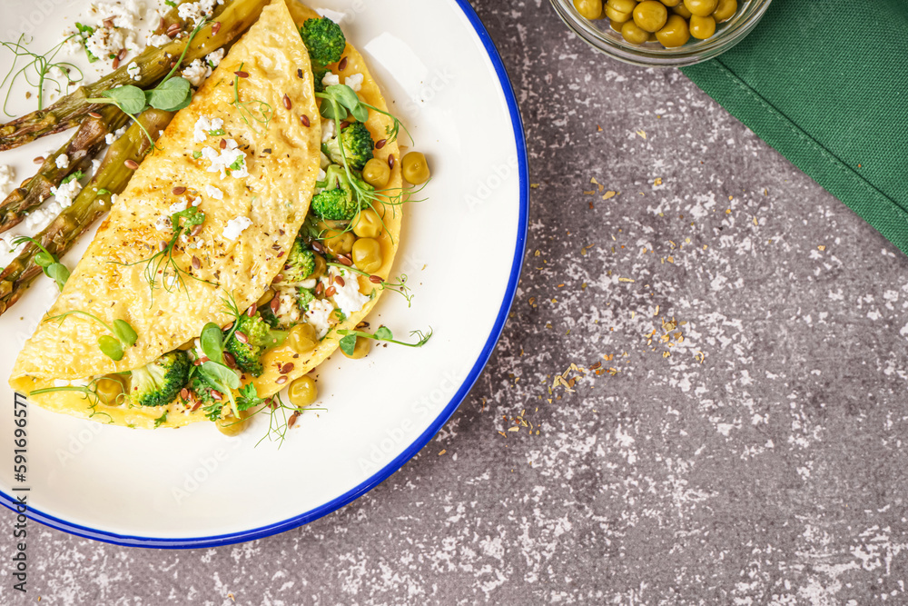 Tasty omelet with broccoli, asparagus and pea on grey background