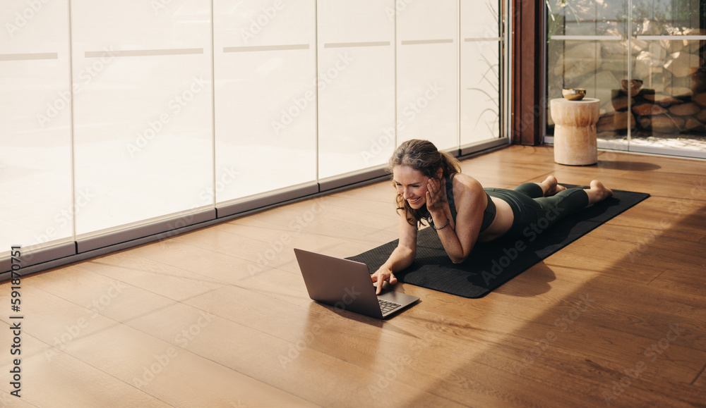 Happy elderly woman joining an online yoga class at home