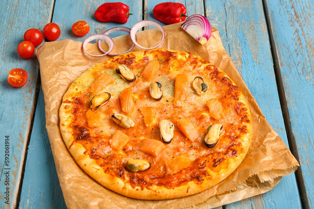 Tasty seafood pizza on blue wooden background