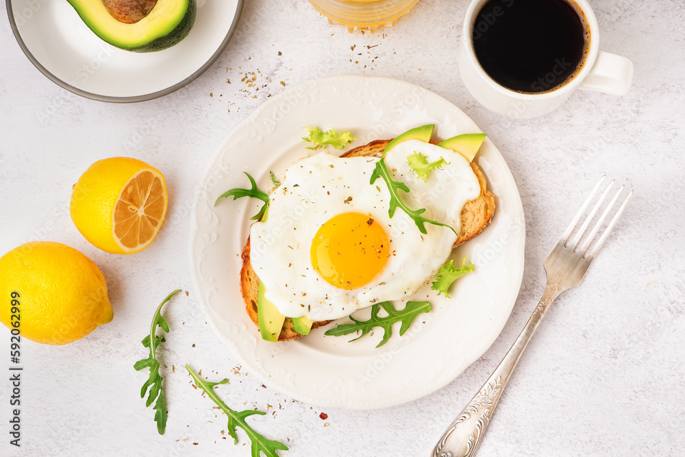 Delicious sandwich with fried egg, arugula and avocado on light background