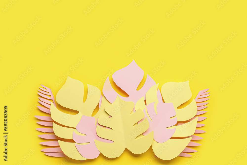 Paper tropical leaves on yellow background