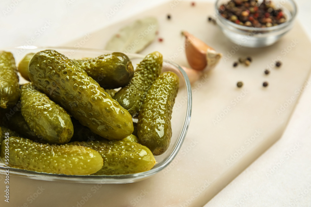 Bowl with tasty fermented cucumbers, board and ingredients on white background