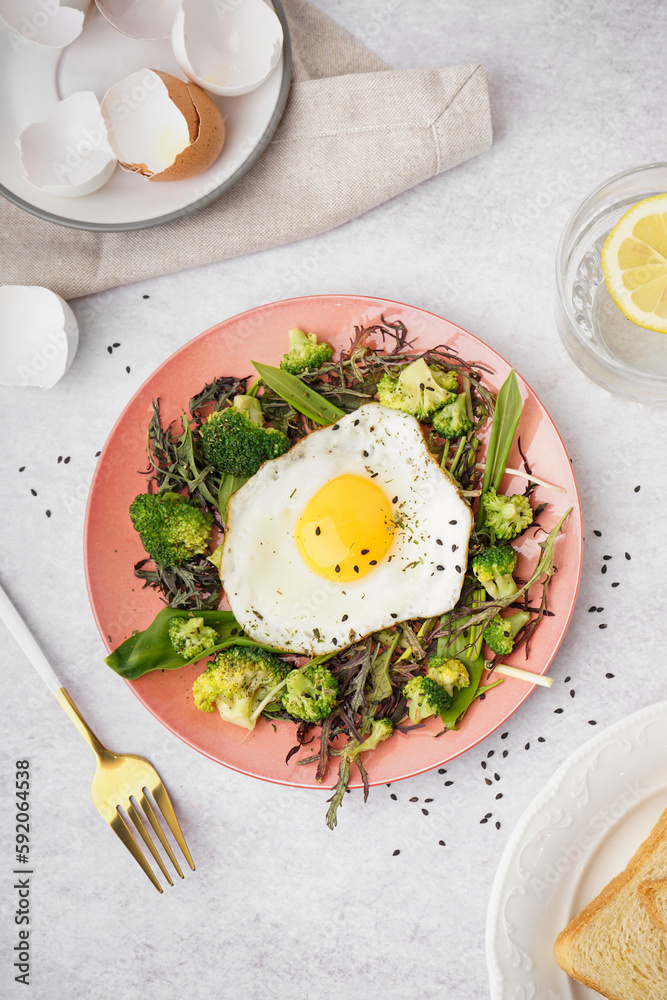 Plate with tasty fried egg and salad on grey background