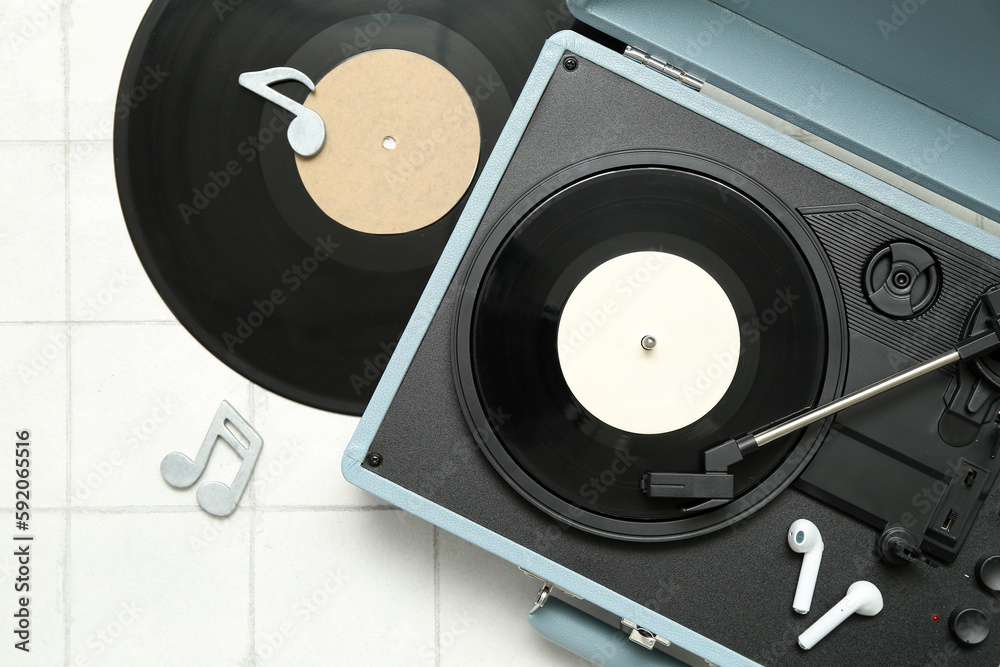 Record player with vinyl disks, earphones and note signs on white tile background