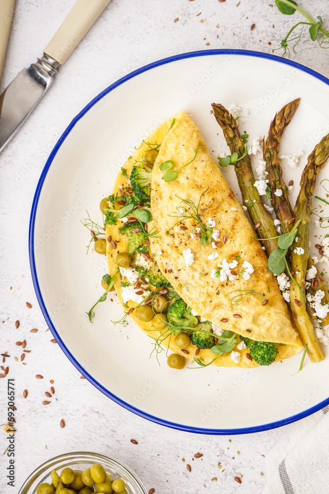 Tasty omelet with broccoli, asparagus and pea on light table