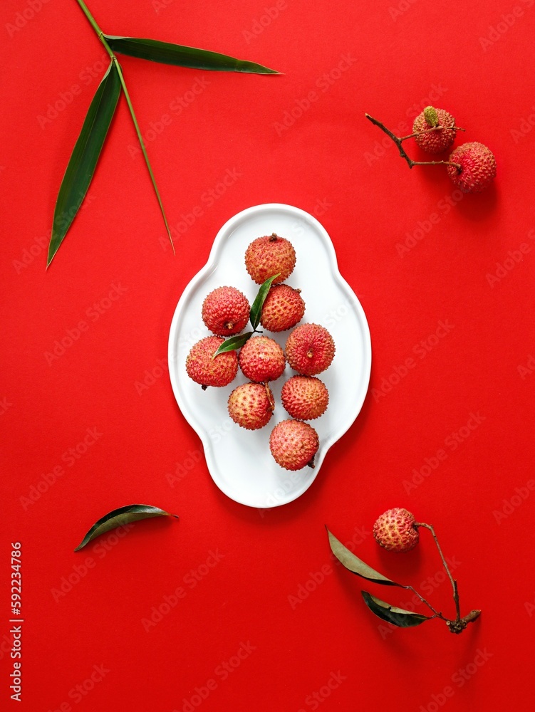 Top view of Lychee tropical fruit on a white plate on a red surface