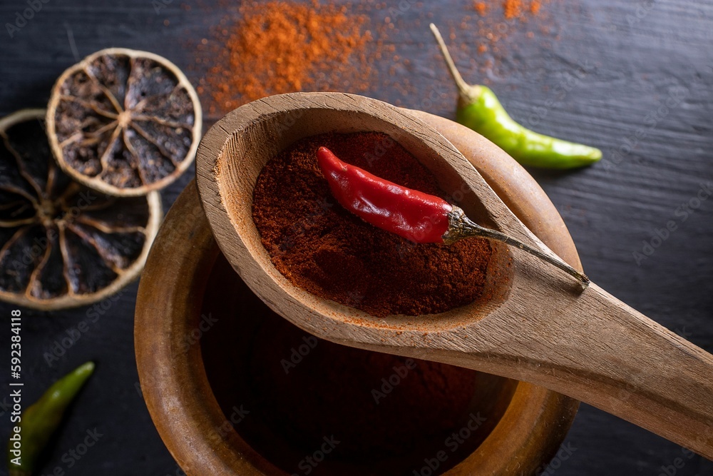 Closeup shot of red hot chili pepper in a wooden spoon with pepper spices