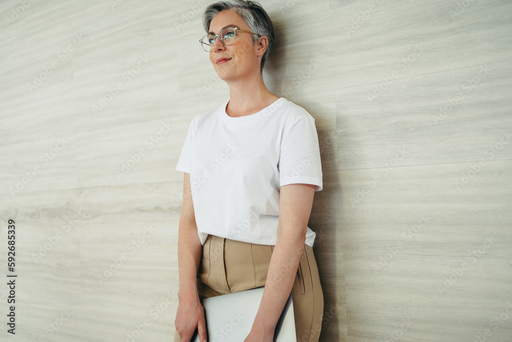 Pensive businesswoman standing against a wall in an office