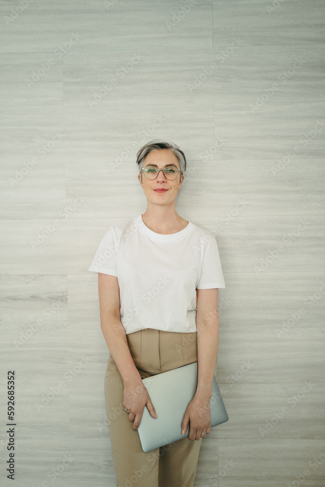 Businesswoman standing against a wall in an office