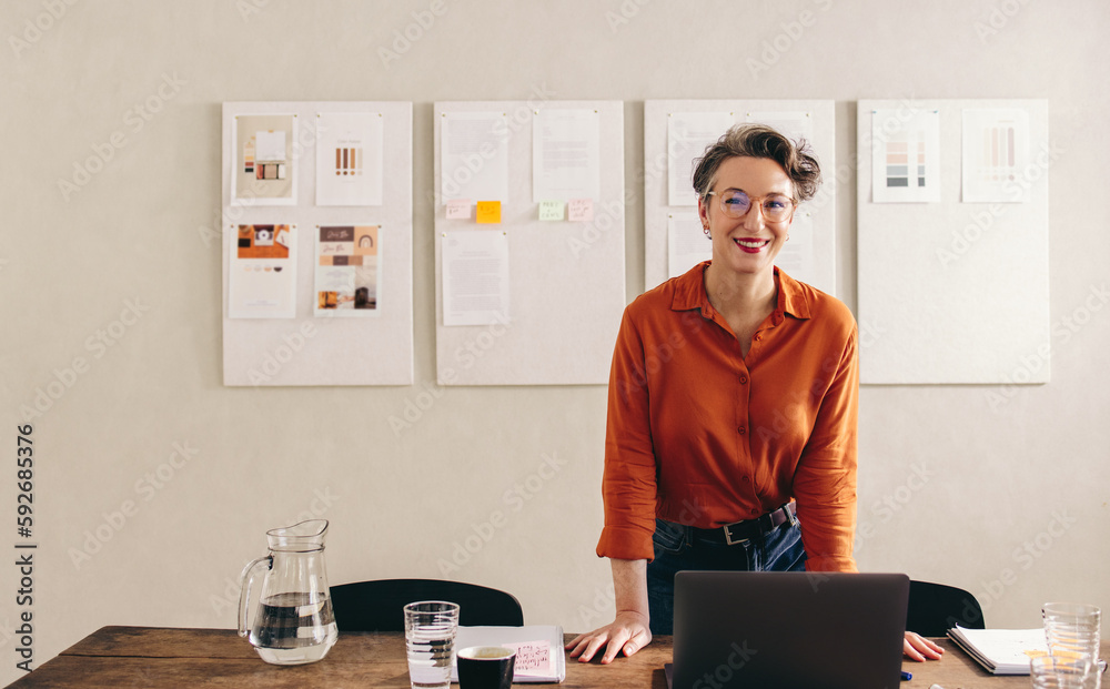 Mature interior designer smiling at the camera in her office