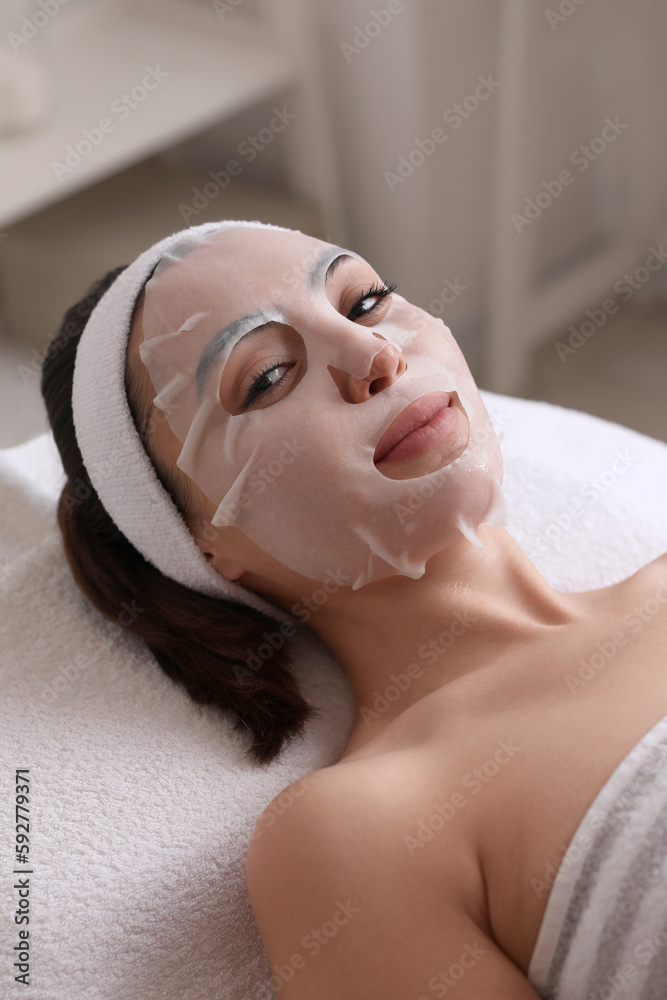 Young woman with sheet mask in beauty salon, closeup