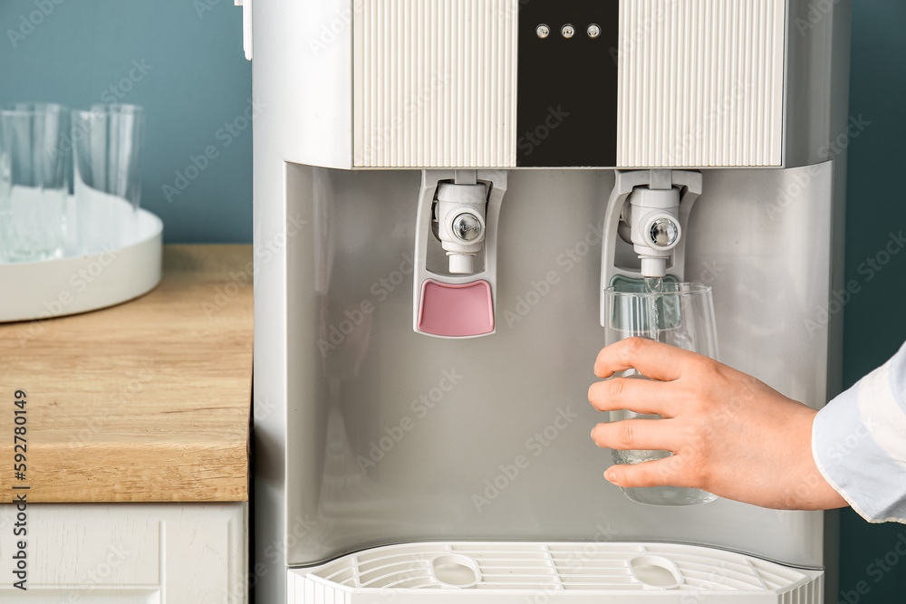 Woman pouring water from modern cooler into glass