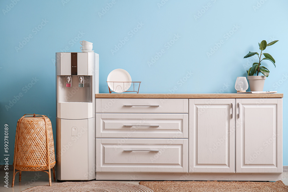 Interior of kitchen with modern water cooler near blue wall