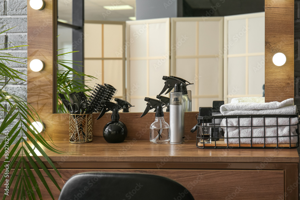 Different hair sprays and accessories on table in beauty salon