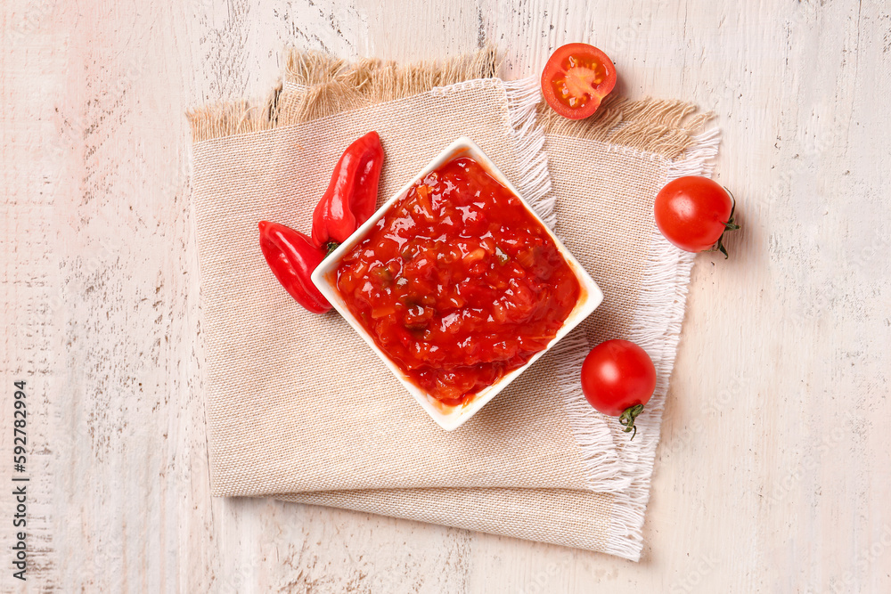 Bowl of delicious salsa sauce and ingredients on white wooden table