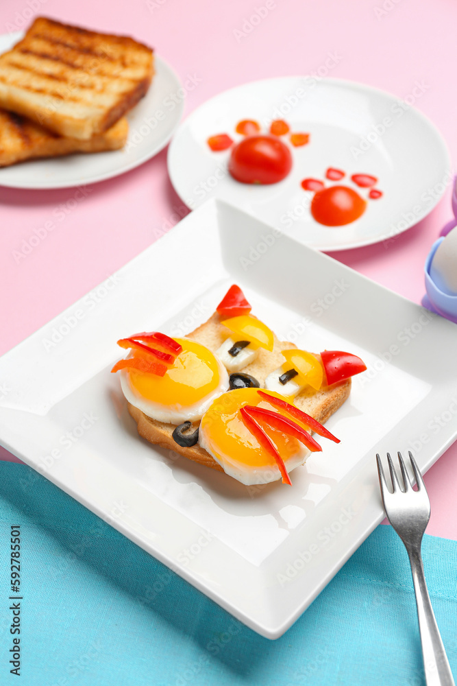 Plate with funny breakfast in shape of cat, toasts and vegetables on pink background