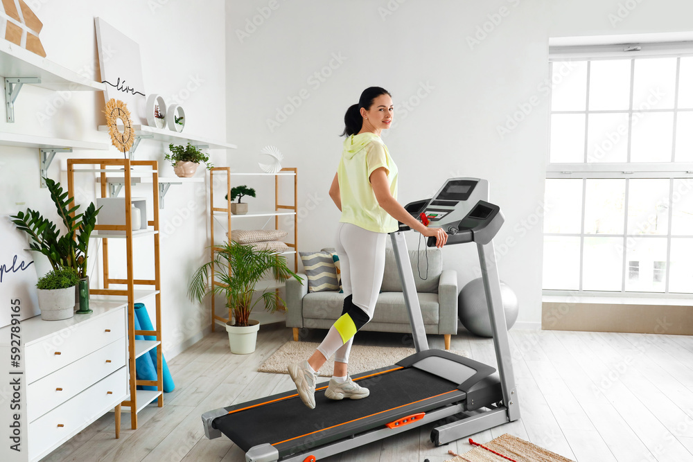 Beautiful woman training on treadmill at home