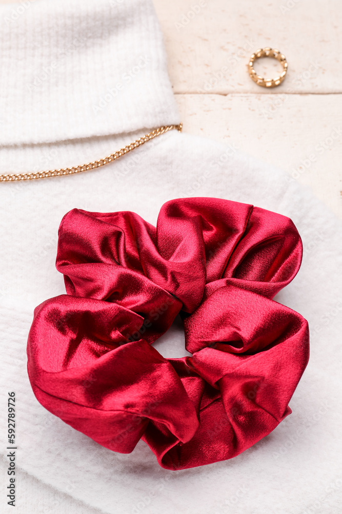 Silk scrunchy with jewelry and sweater on white wooden background, closeup