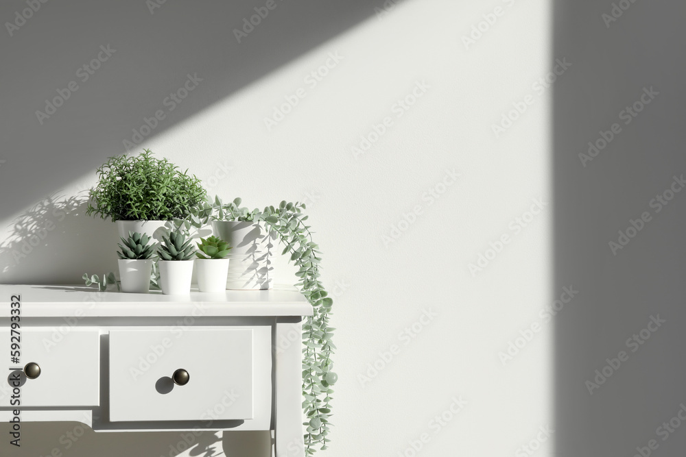 Artificial plants on table near light wall