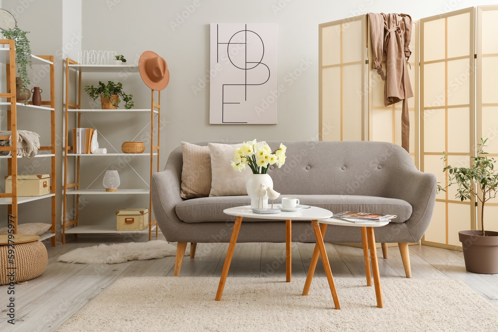 Interior of living room with grey sofa, tables and folding screen