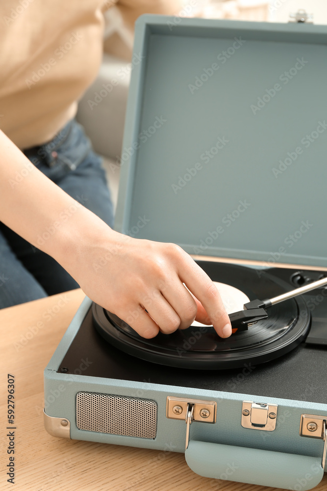 Woman using record player at home, closeup