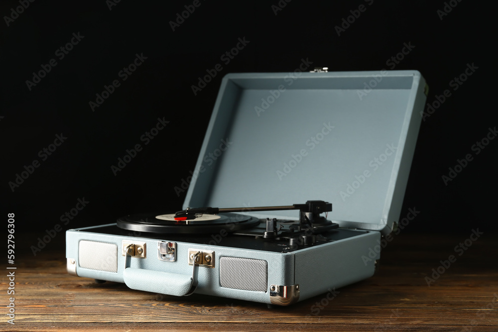 Record player with vinyl disk on dark wooden background