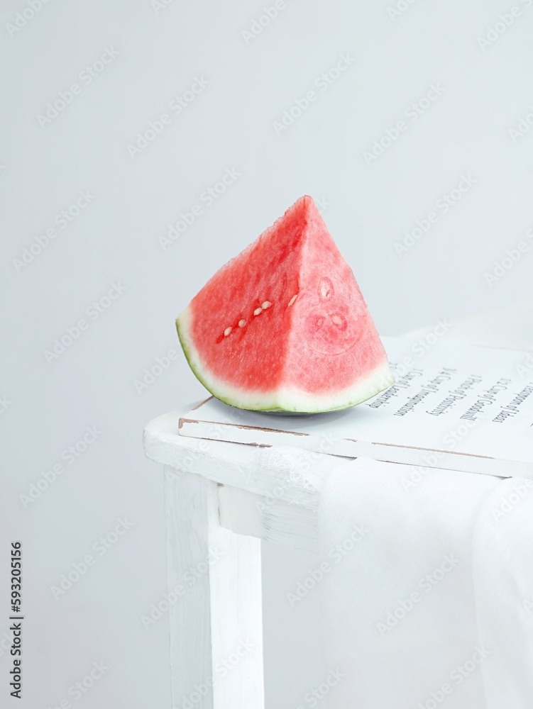 Vertical shot of a slice of watermelon on a white wooden board on a white background