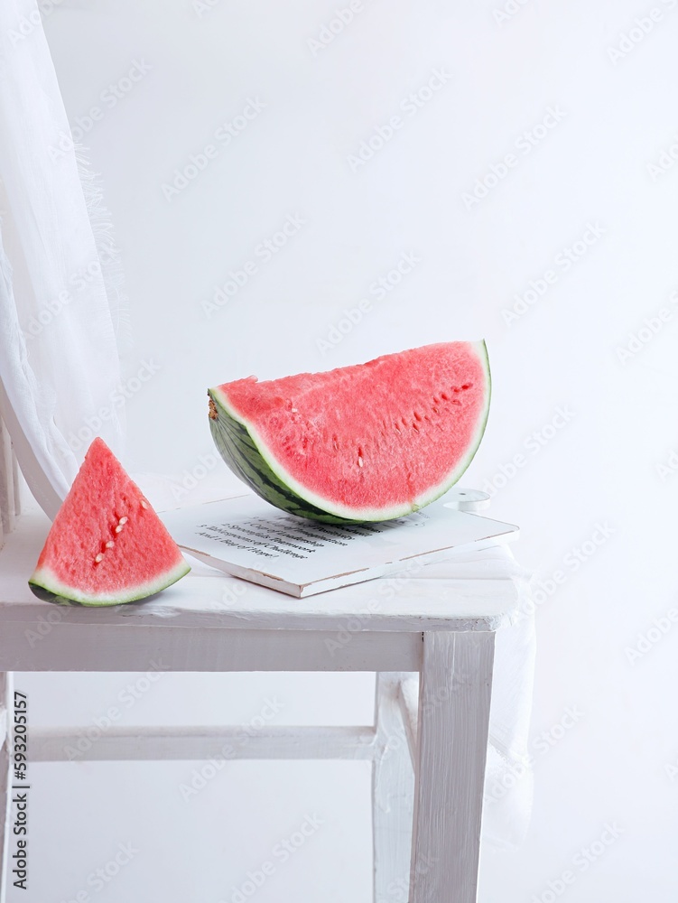 Vertical shot of slices of watermelon on a white wooden board on a white background