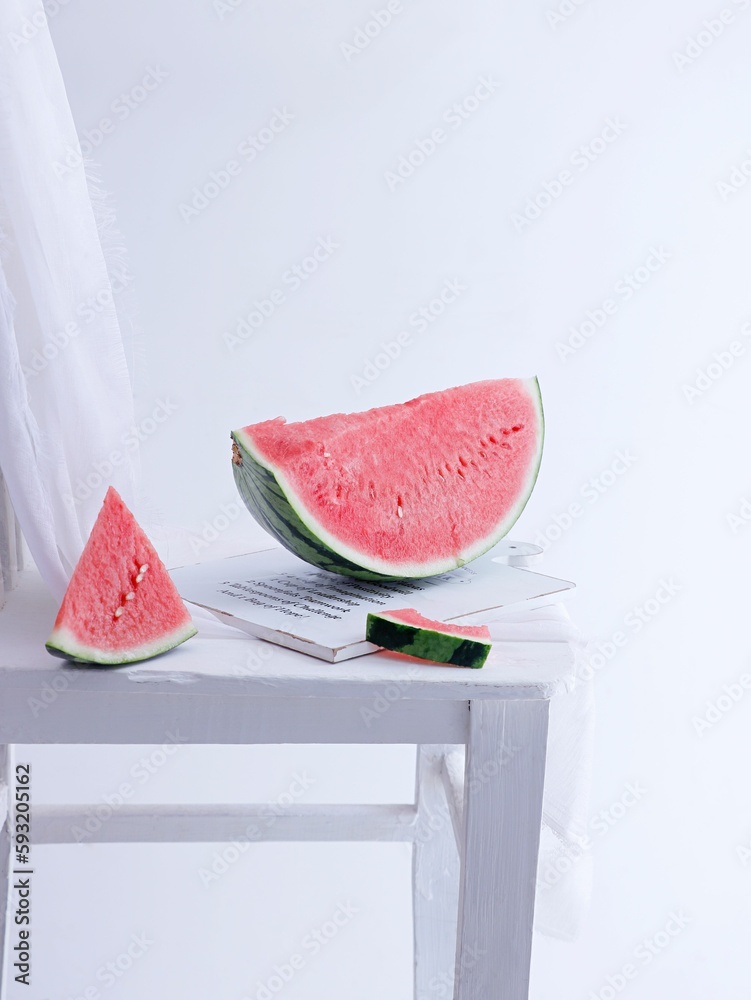 Vertical shot of slices of watermelon on a white wooden board on a white background