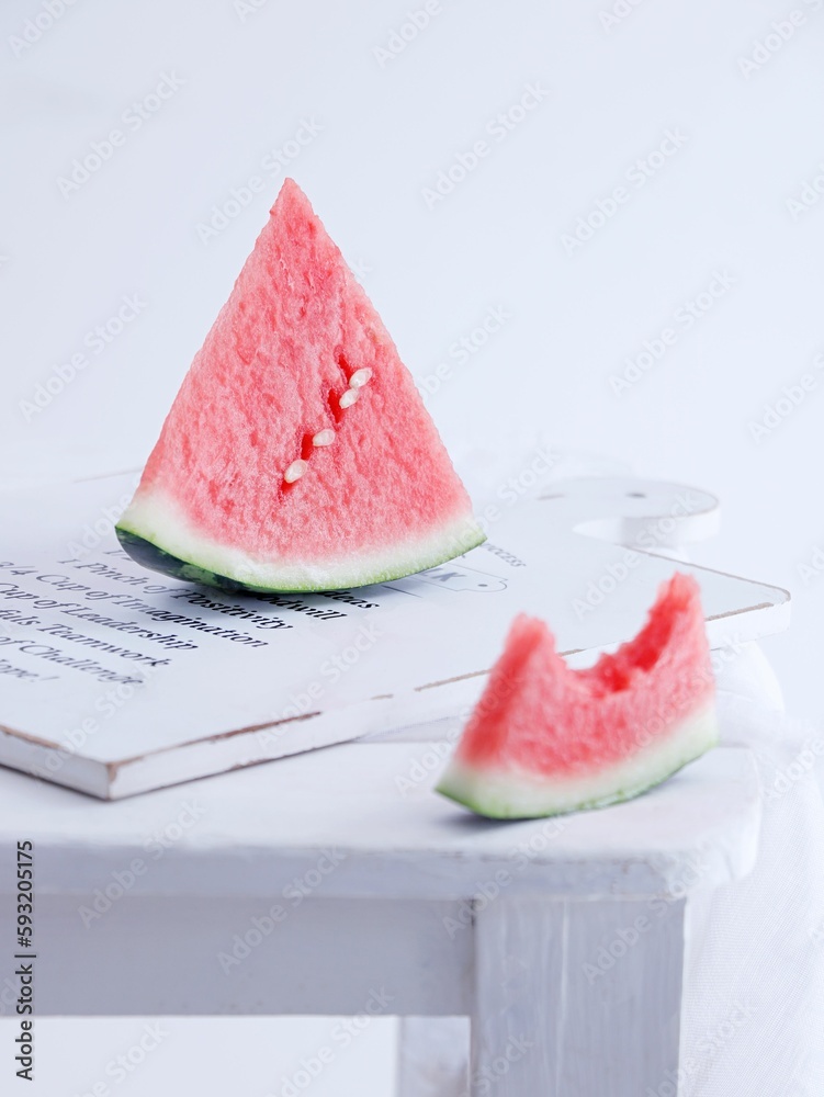 Vertical shot of slices of watermelon on a white wooden board on a white background