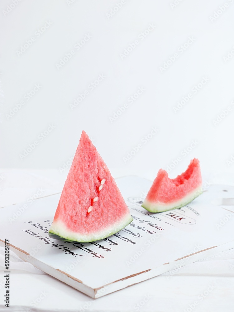 Vertical shot of slices of watermelon on a white wooden board on a white background