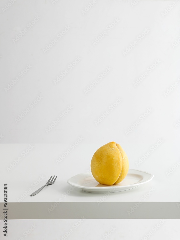 Vertical shot of an unripe peach with water droplets on a plate with a fork