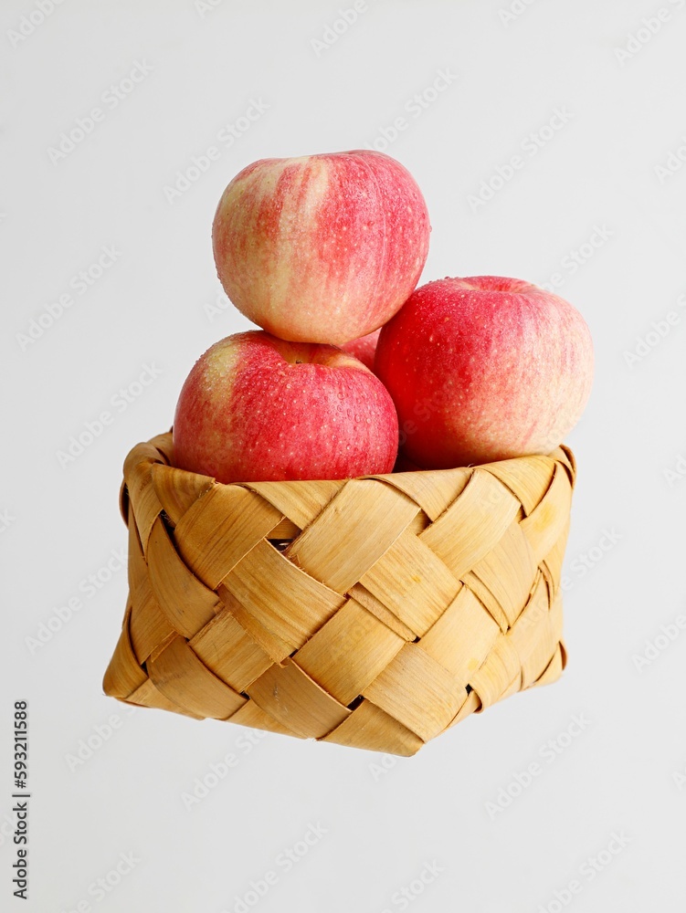 Close-up shot of red apples in a wicker basket on a white table