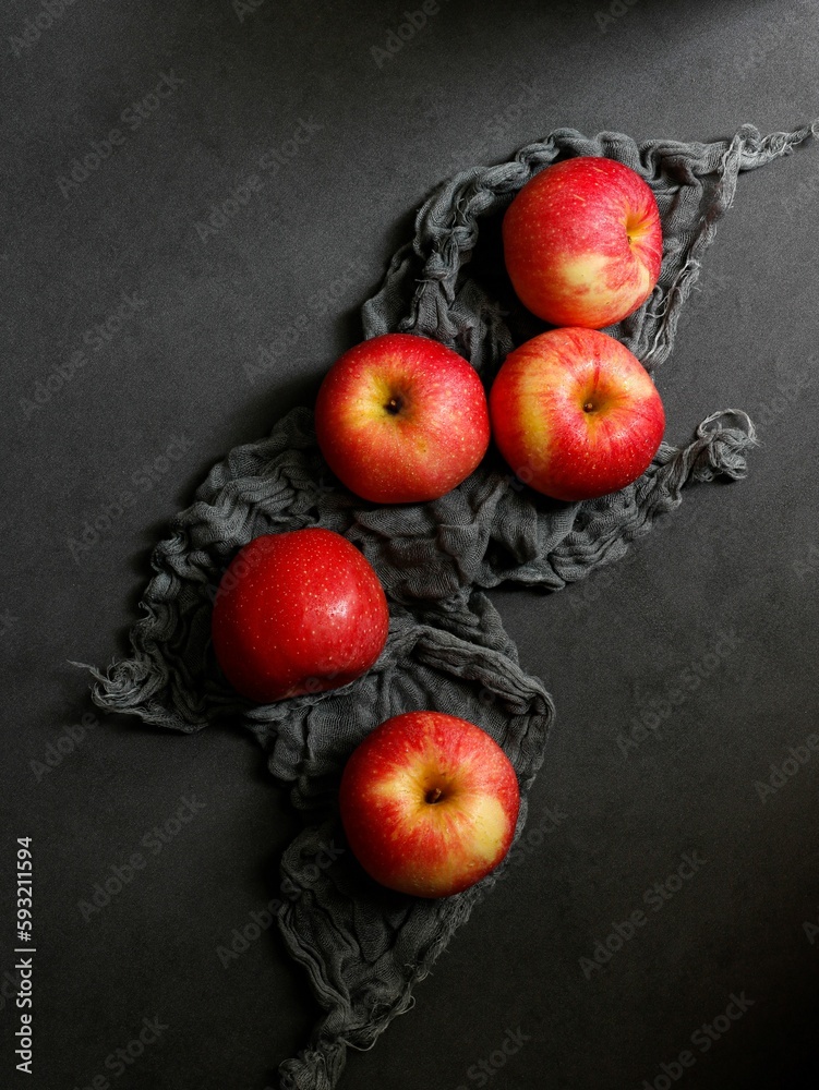 Vertical shot of red apples with a black fabric on a black table