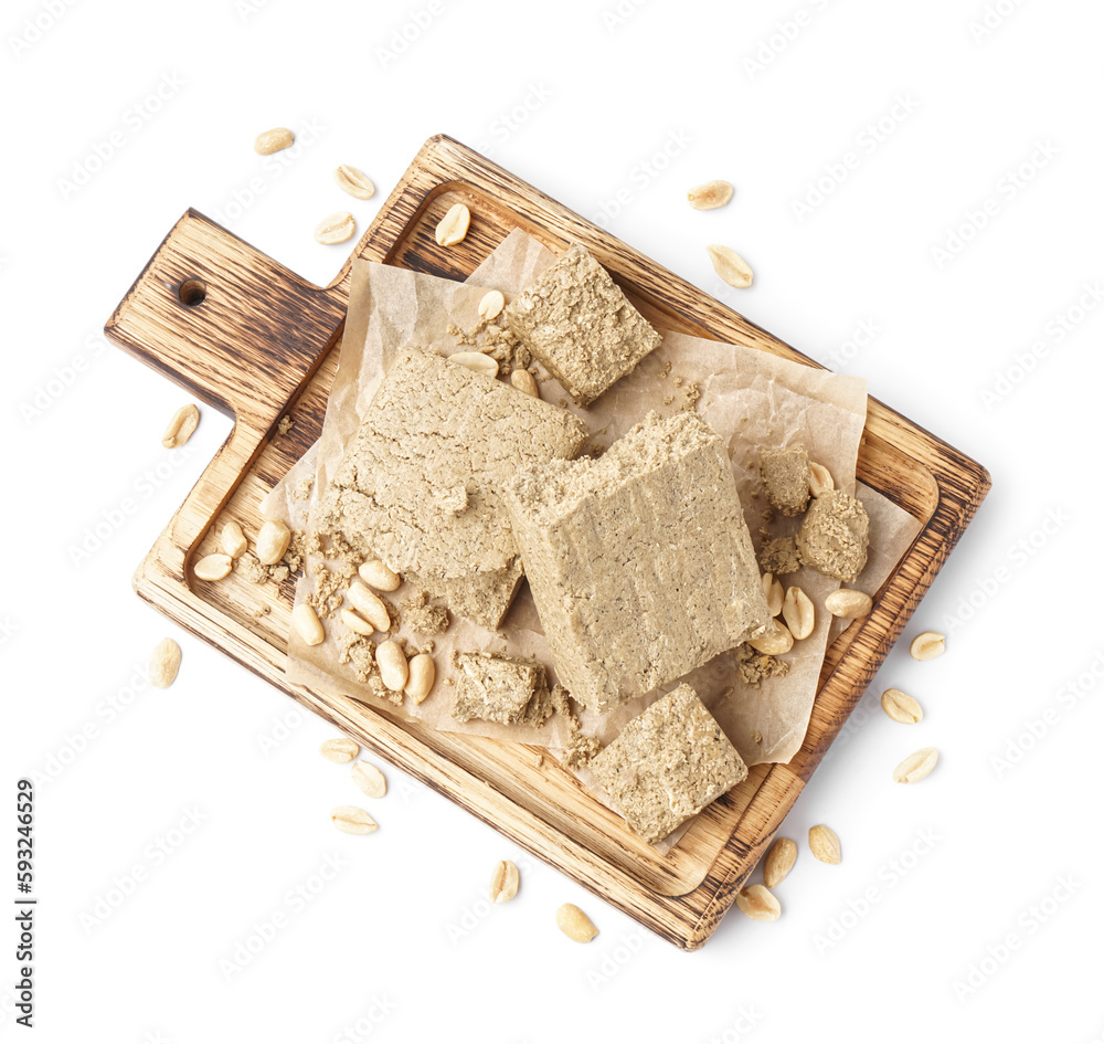 Wooden board with tasty halva and peanuts on white background