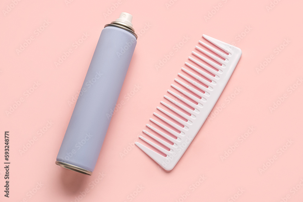 Bottle of hair spray and comb on color background