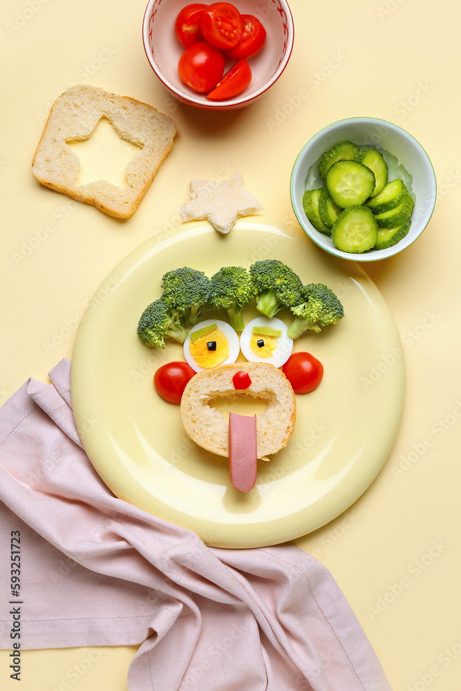 Plate with funny breakfast in shape of face and vegetables on beige background