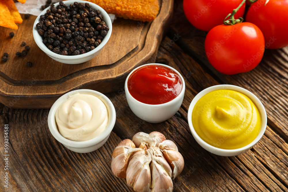 Composition with bowls of different sauces and garlic on wooden table